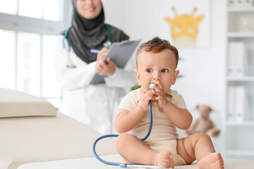 Cute baby boy playing with stethoscope in clinic