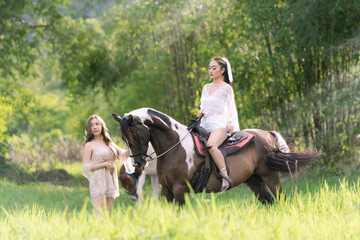 Two Beautiful woman and horse in the field at spring. Happy woman in white dress with horse in summer field forest.