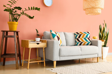 Interior of stylish living room with sofa, wooden table and pink wall