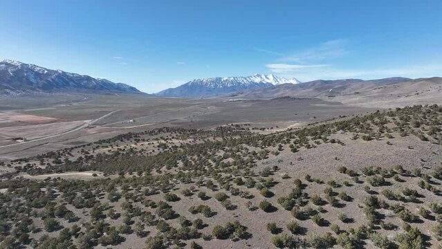 Aerial mountain valley juniper cedar trees hills Utah. Aerial rural farming community agricultural economy. Spring weather mountain valley green agriculture field. Seasonal rural farm city.