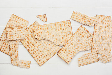 Torn Jewish flatbread matza for Passover on white wooden background