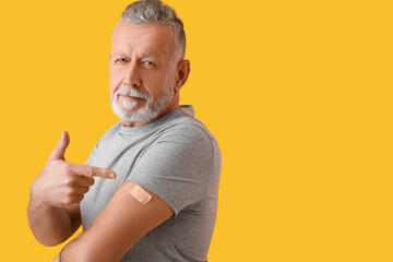 Mature man with applied nicotine patch on color background. Smoking cessation