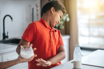 A boy in red shirt refusing from milk
