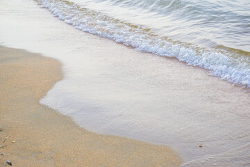 Sea wave on sandy beach morning sun light