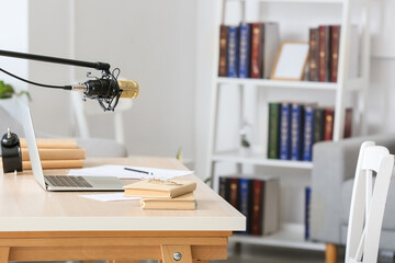 Modern workplace with laptop, books and microphone in room