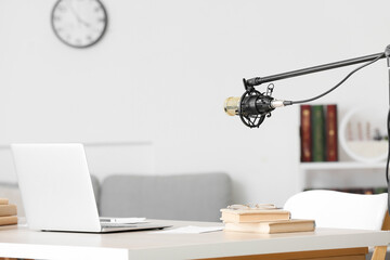 Modern workplace with laptop, books and microphone in room