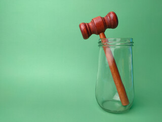Gavel and glasses jar on a green background with copy space.
