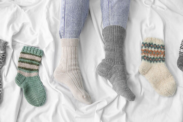 Female legs in different warm socks on bed. Concept of heating season