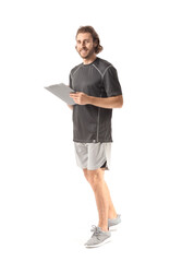 Sporty male trainer with clipboard on white background