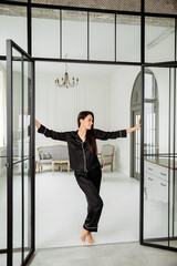 Young  woman in black silk .pajamas possing at home
