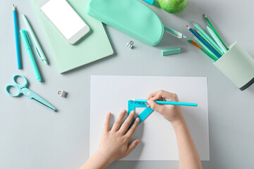 Child's hands with stationery and mobile phone on white background
