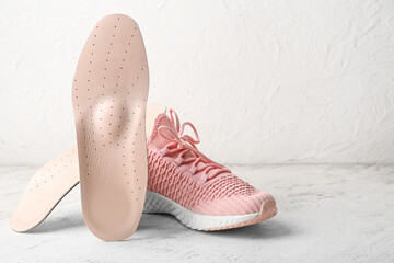 Orthopedic insoles and shoe on light background