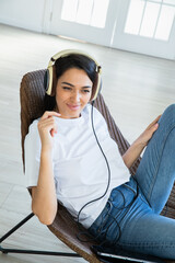 Happy woman with teadphones sitting at chear  at home
