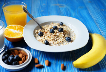 oatmeal with fresh berries on white plate with orange juice and milk