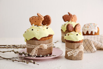 Delicious Easter cakes decorated with cookies and willow branches on light background