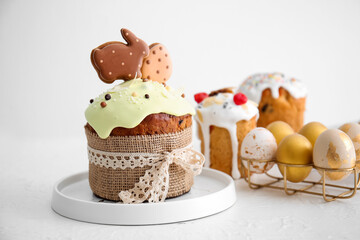 Delicious Easter cake decorated with cookies and painted eggs on light background