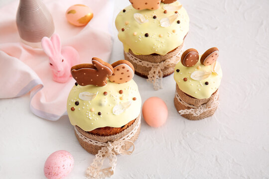 Delicious Easter cakes decorated with cookies and painted eggs on light background