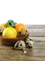 Bowl with painted Easter eggs on table against white background