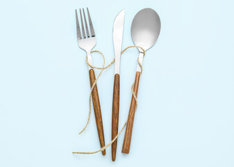 Elegant cutlery with rope on blue background