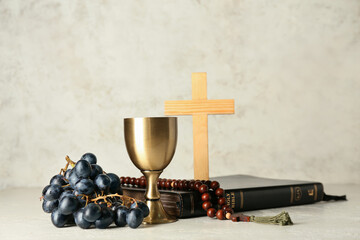 Obraz na płótnie Canvas Cup of wine with Holy Bible, rosary and cross on light background