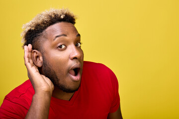Dark-skinned surprised guy leaned forward leaning his hand against his ear, listening to last...