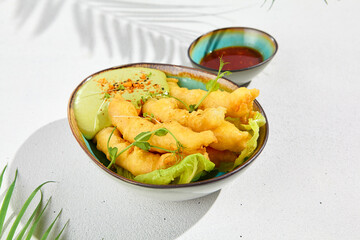 Tempura shrimps with wasabi sauce in ceramic bowl in minimal style. Fried prawns with deep on white background with hard shadow from leaves. Asian food in contemporary style. Modern food.