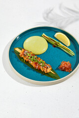 Squid yakitori in ceramic dish on white background. Japanese skewered squid with wasabi sauce. Grilled kalmar on bamboo skewer in asian style. Food menu for izakaya. Summer pan asian menu. © Ryzhkov