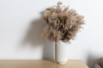 Minimalist composition of dried pampas grass in a cylindrical ceramic vase as home decoration.