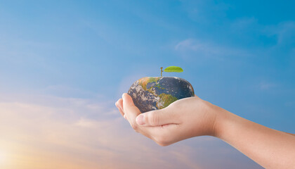 Child hands holding apple globe earth over blurred sunset sky background. World environment day concept