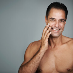 My secret is a good moisturizer. Studio portrait of a handsome mature man applying moisturizer to...