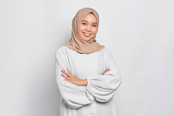 Smiling young Asian Muslim woman crossed arms and looking confident isolated over white background