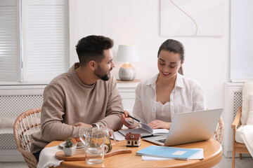 Happy young couple discussing family budget and new house buying at home. Mortgage concept