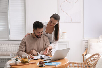 Happy young couple discussing family budget and new house buying at home. Mortgage concept
