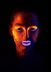 Glowing in the dark. A young woman with with neon paint on her face posing.