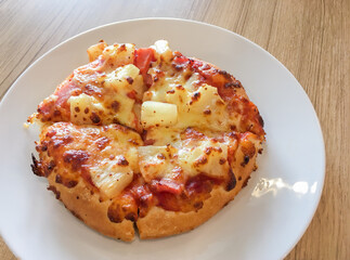 Hawaiian pizza and cheese on the dish