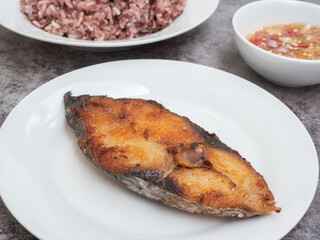 Deep fried Indo-Pacific king mackerels or king mackerels fish with spicy fish sauce and rice berry