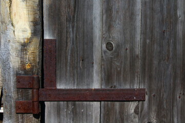 Wooden Fence Door View with Weathered Wall Planks, Old Rusty Hinges and Chains. Agricultural Livestock Building Tree Texture Background