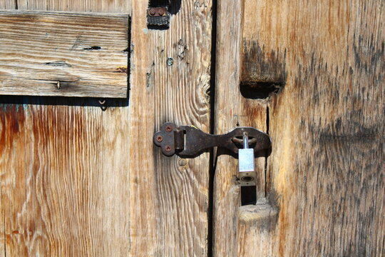 Padlock hanging on old wooden door