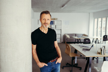 Fototapeta premium older casual businessman leaning relaxed against a pillar in the office