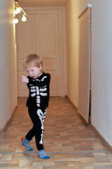 A child in a skeleton costume is dancing in the hallway of the house - 495848332
