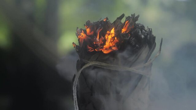 Closeup of a glowing sage smudge stick releasing relaxing aroma smoke to a room