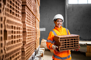 Portrait of female worker moving clay bricks in construction materials factory.