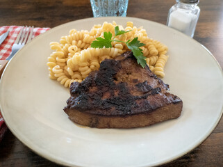grilled beef liver with pasta on a plate