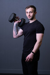 A guy with dumbbells in a black T-shirt muscular man background holding, for aged headphones in male and workout health, adult caucasian. Shirt person lifting, bodybuilding young