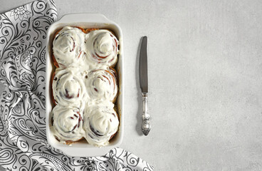 Cinnamon rolls or cinnabon, homemade sweet traditional dessert buns with white cream sauce on white gray background, copy space.