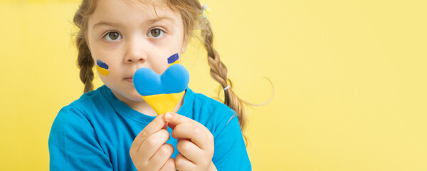The girl holds a heart of yellow and blue color of the Ukrainian flag. No war in Ukraine concept