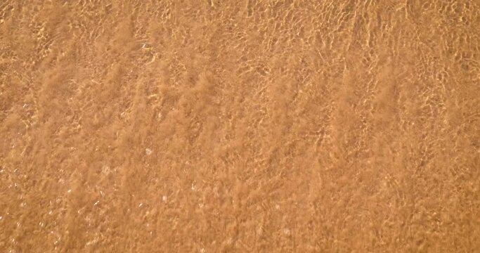 Sun picture on the sand. A view of a sad drawn sun in warm sea waves on the sand.