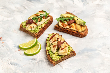 Grilled Halloumi cheese, avocado guacamole, arugula on roasted bread. Food recipe background. Close up