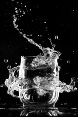glass with water ice and splashes on a black background
