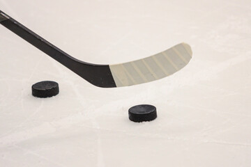 Ice hockey stick with black hockey puck near on ice details.